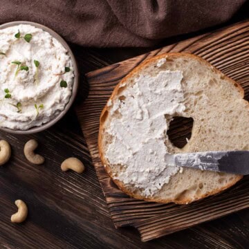 Vegan cream cheese spread on a bagel and in a small bowl.