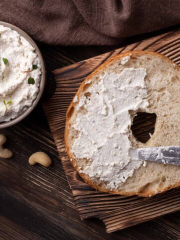 Vegan cream cheese spread on a bagel and in a small bowl.