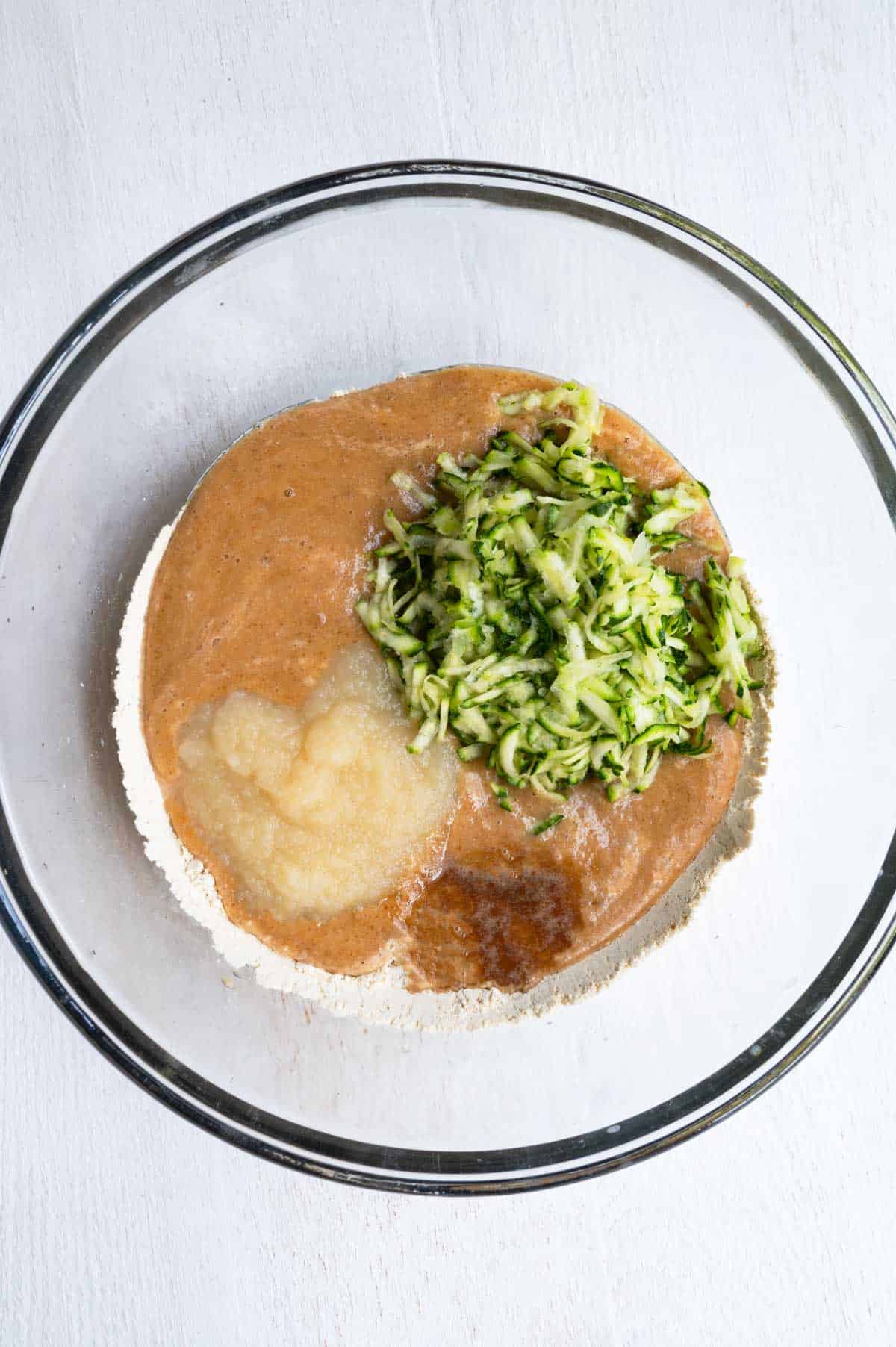 Grated zucchini, date paste, chickpea flour, apple sauce, flaxseed meal, and psyllium husk in a large bowl.
