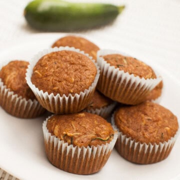 High-protein zucchini muffins beside a whole zucchini.