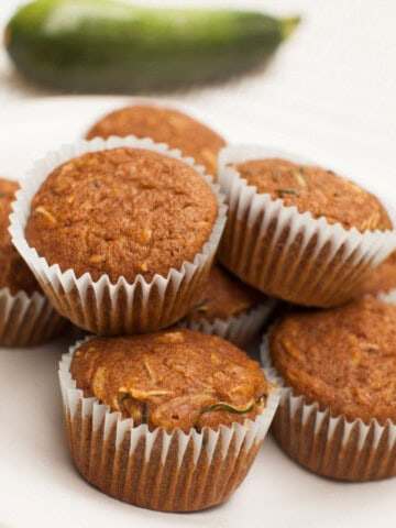 High-protein zucchini muffins beside a whole zucchini.