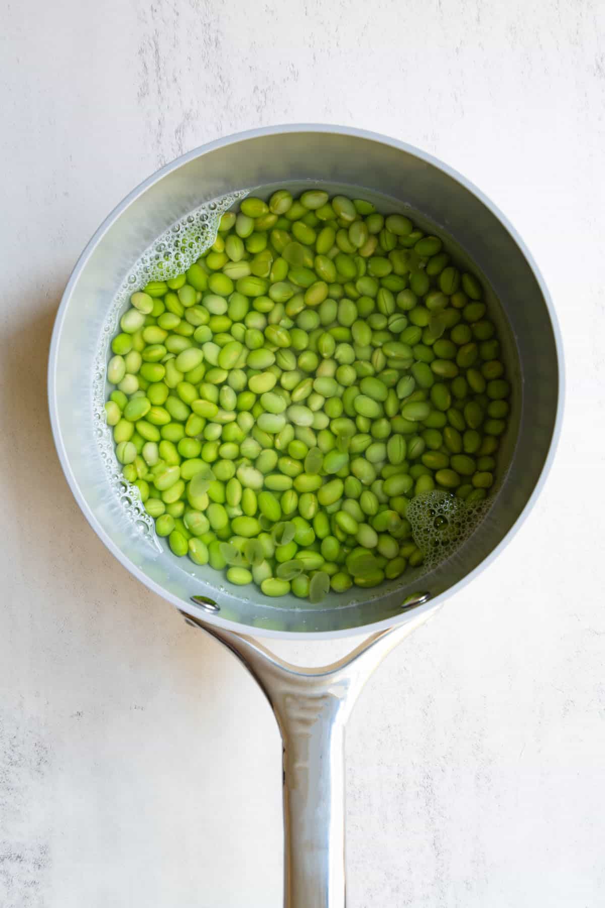 Simmered edamame in a saucepan.