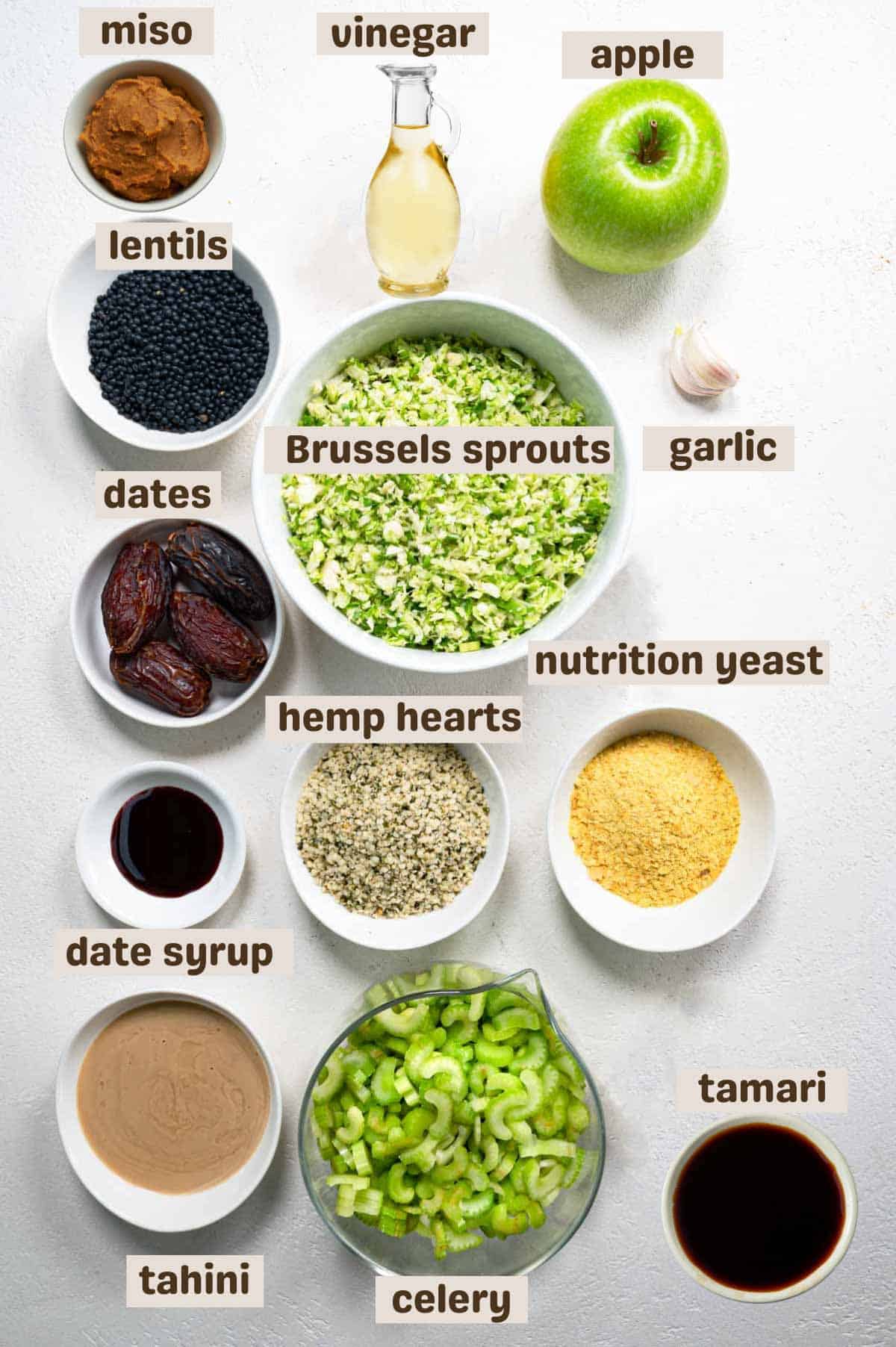 Lentils, tahini, garlic, rice vinegar, tamari, date syrup, chopped dates, nutritional yeast, celery, apple, and shaved Brussels sprouts.
