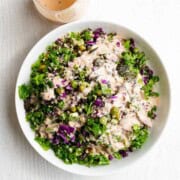 Protein Lentil quinoa salad in a white bowl topped with tahini dressing.