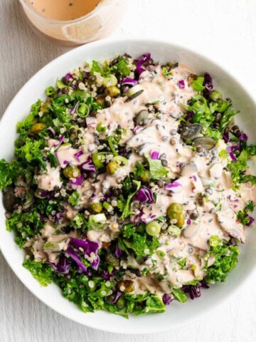 Protein Lentil quinoa salad in a white bowl topped with tahini dressing.