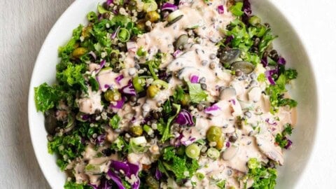 Protein Lentil quinoa salad in a white bowl topped with tahini dressing.