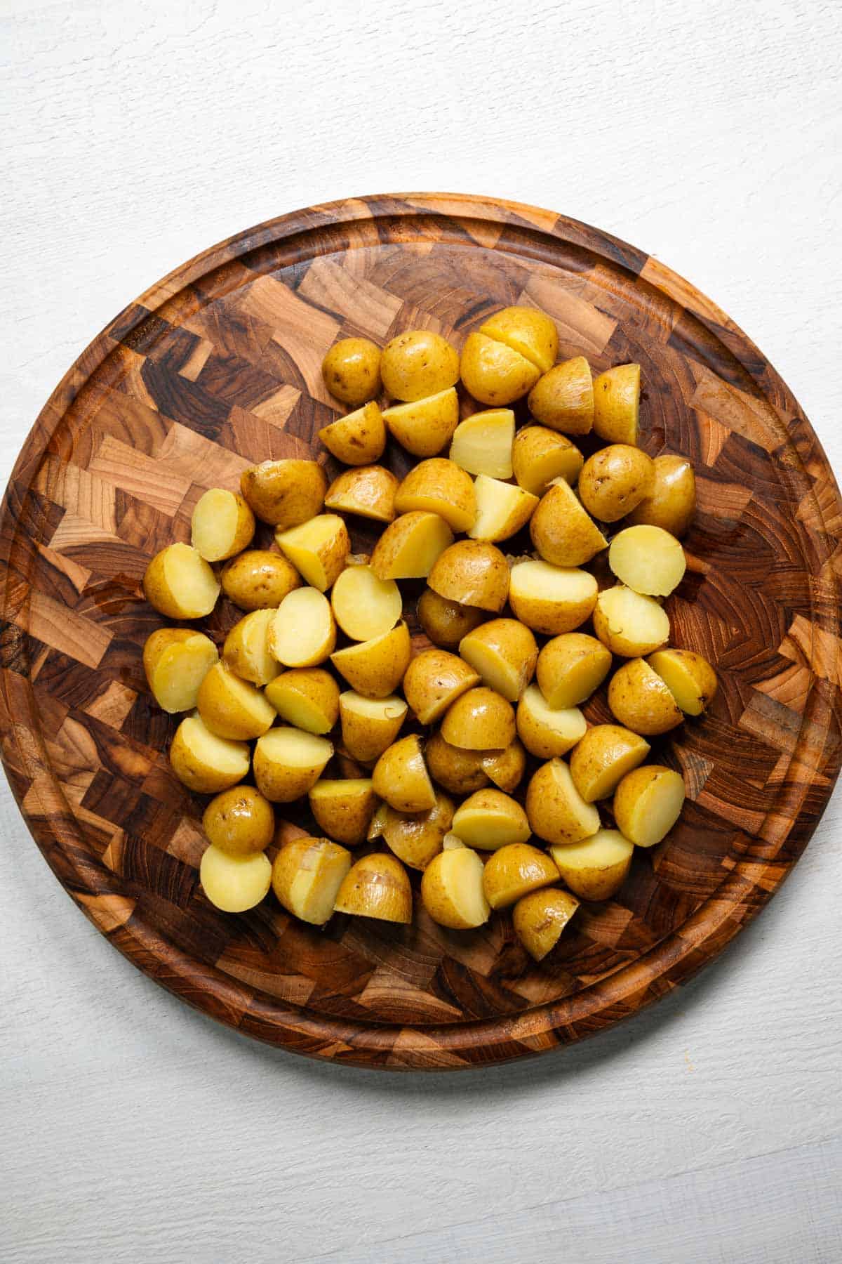 Sliced baby potatoes on a wooden cutting board.