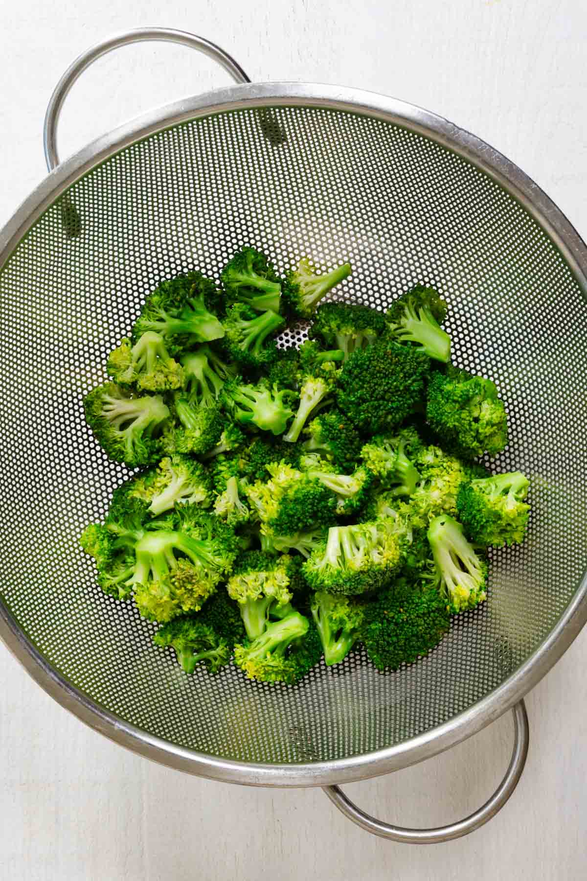 Steamed broccoli in a colander.