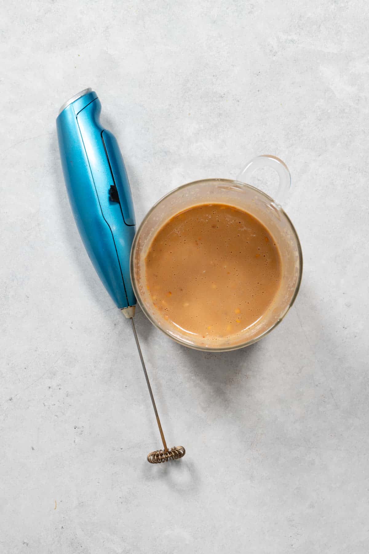 Light tahini or peanut dressing next to a frother.
