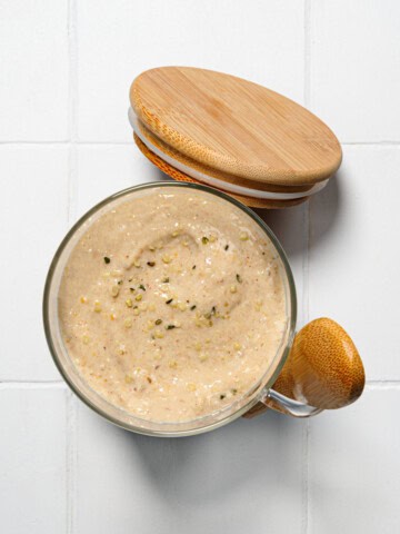 Blended protein oats in a glass serving jar with wooden spoon and lid.