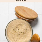 Blended protein oats in a glass serving jar with wooden spoon and lid.