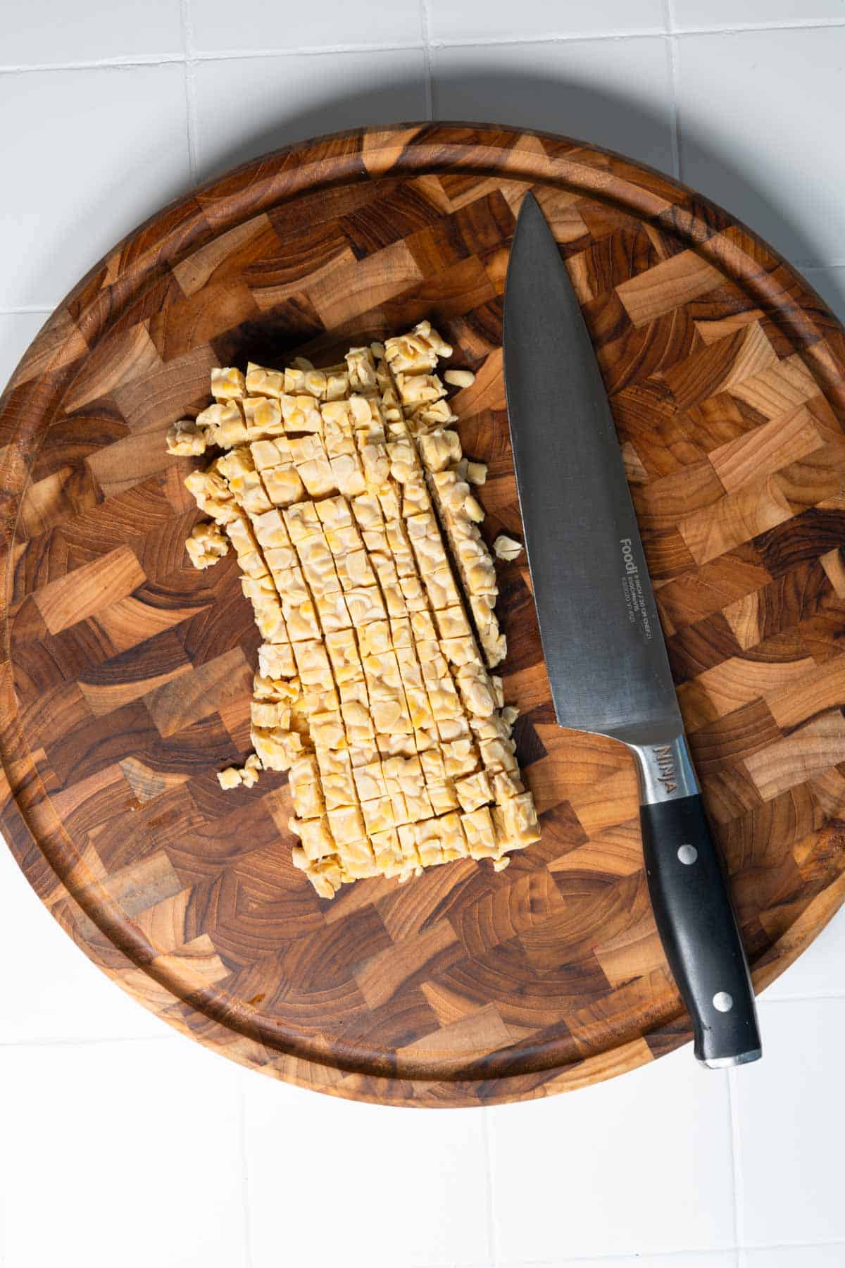 Chopped steamed tempeh on a cutting board.