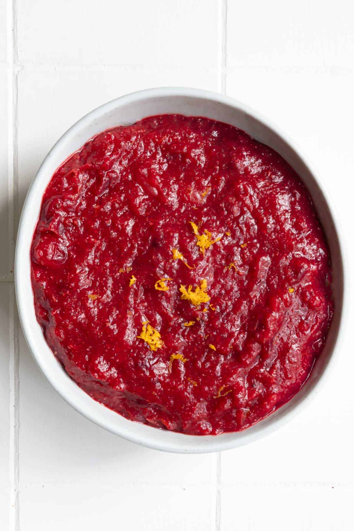 Cranberry sauce in a bowl with a sprinkle of lemon zest.