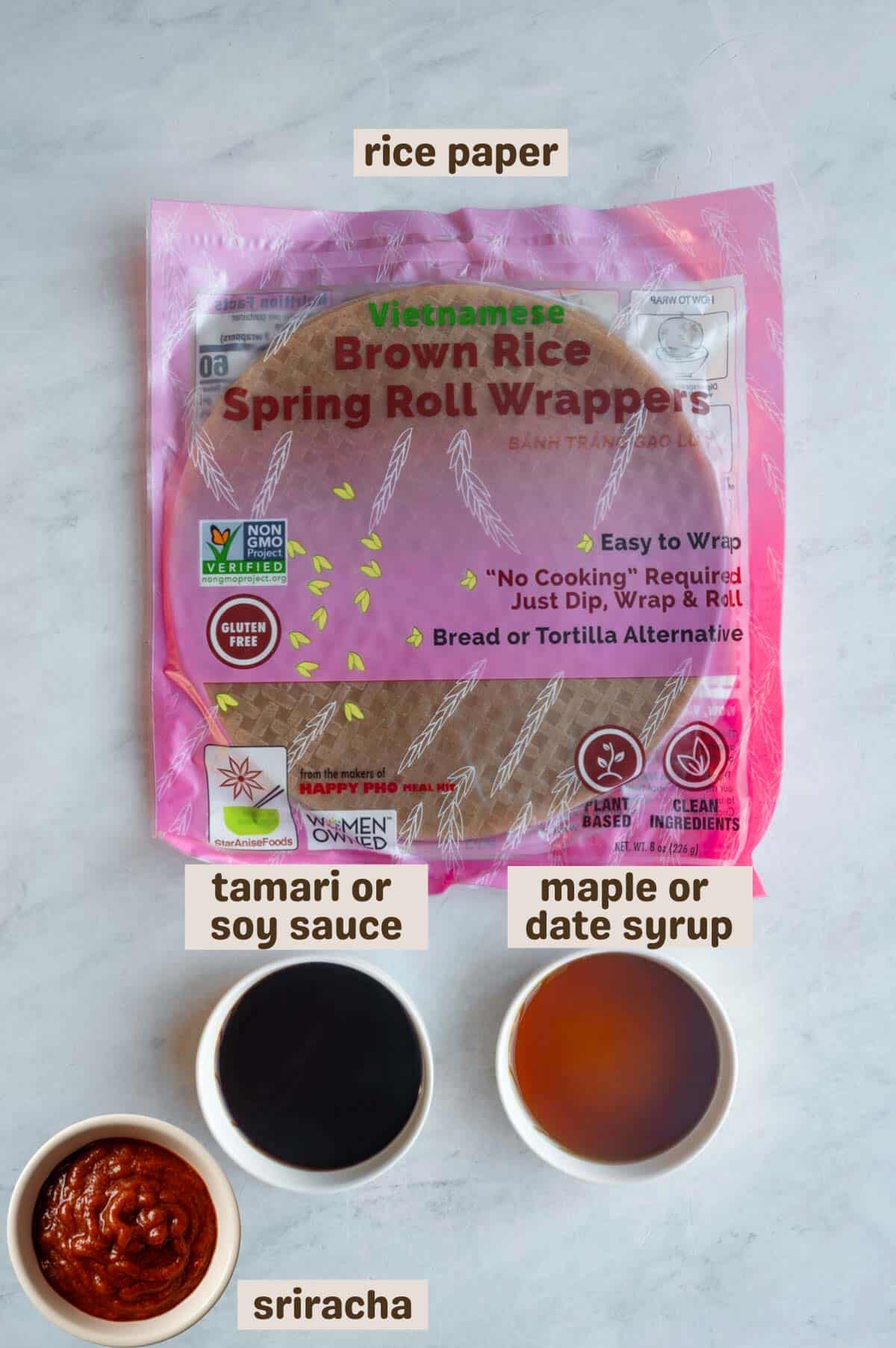 Brown rice spring roll wrappers, soy sauce, and maple syrup on a grey backdrop.