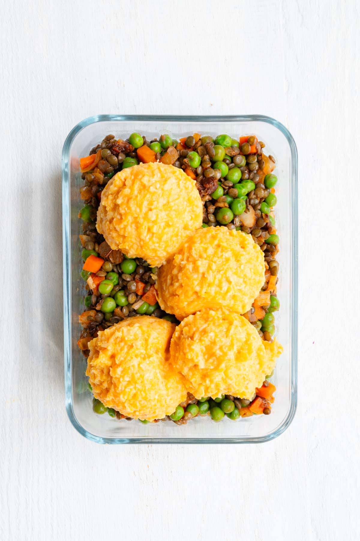 Vegetarian Lentil Shepherd's Pie filling and scooped topping in a glass baking dish.