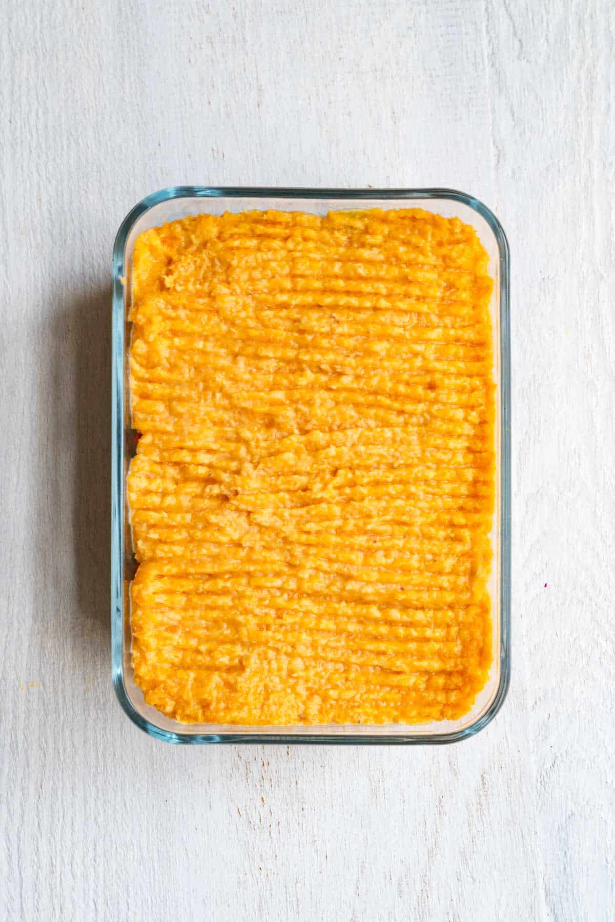 Unbaked vegetarian Lentil Shepherd's Pie in a glass baking dish.