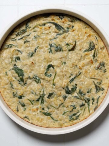 Creamy vegan spinach and artichoke dip in a round baking dish.