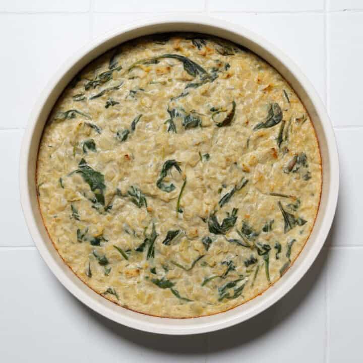Creamy vegan spinach and artichoke dip in a round baking dish.