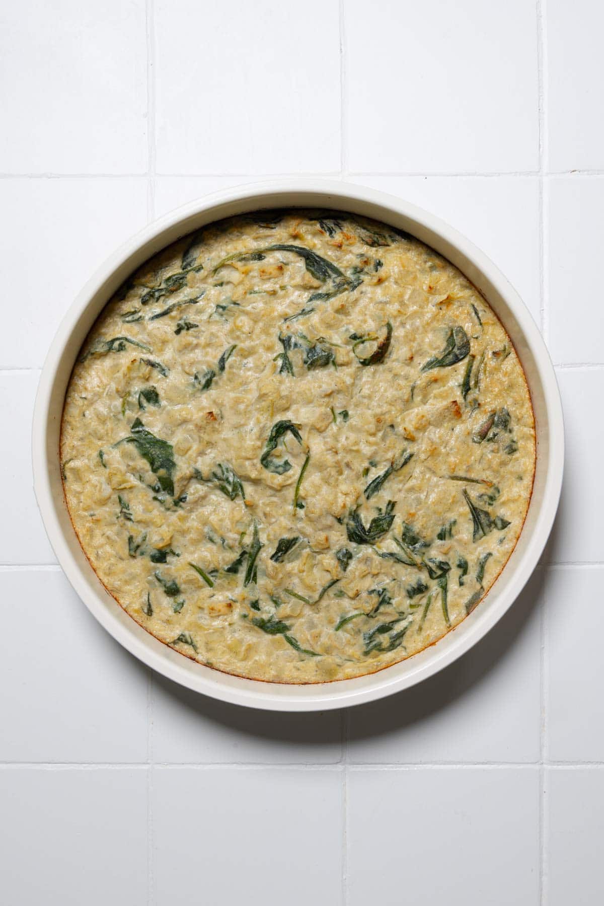 Creamy vegan spinach and artichoke dip in a round baking dish.