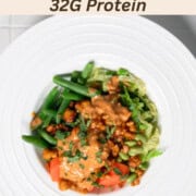 Steamed vegetable bowl with carrots, cabbage, edamame, tempeh, green beans, and peanut sauce.