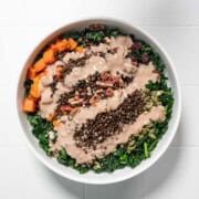 Thanksgiving salad with creamy tahini dressing in a white bowl.