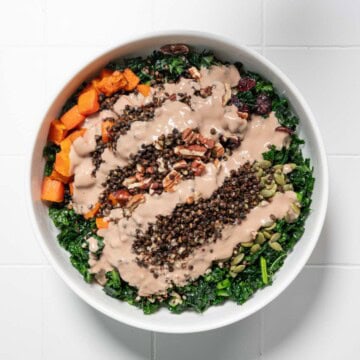 Thanksgiving salad with creamy tahini dressing in a white bowl.