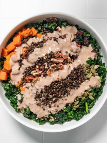 Thanksgiving salad with creamy tahini dressing in a white bowl.