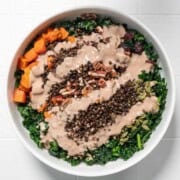 Thanksgiving salad with creamy tahini dressing in a white bowl.