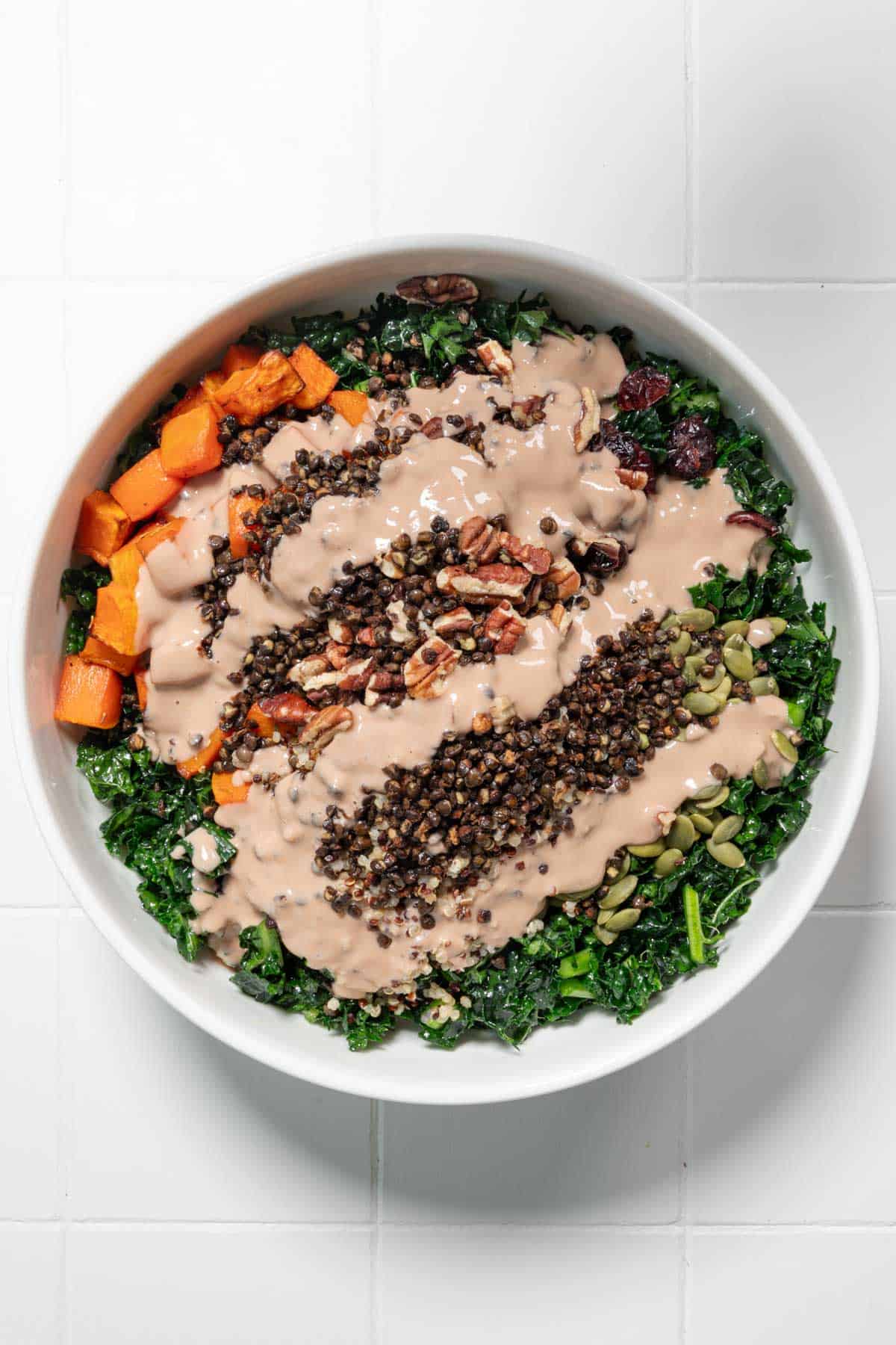 Thanksgiving salad with creamy tahini dressing in a white bowl.