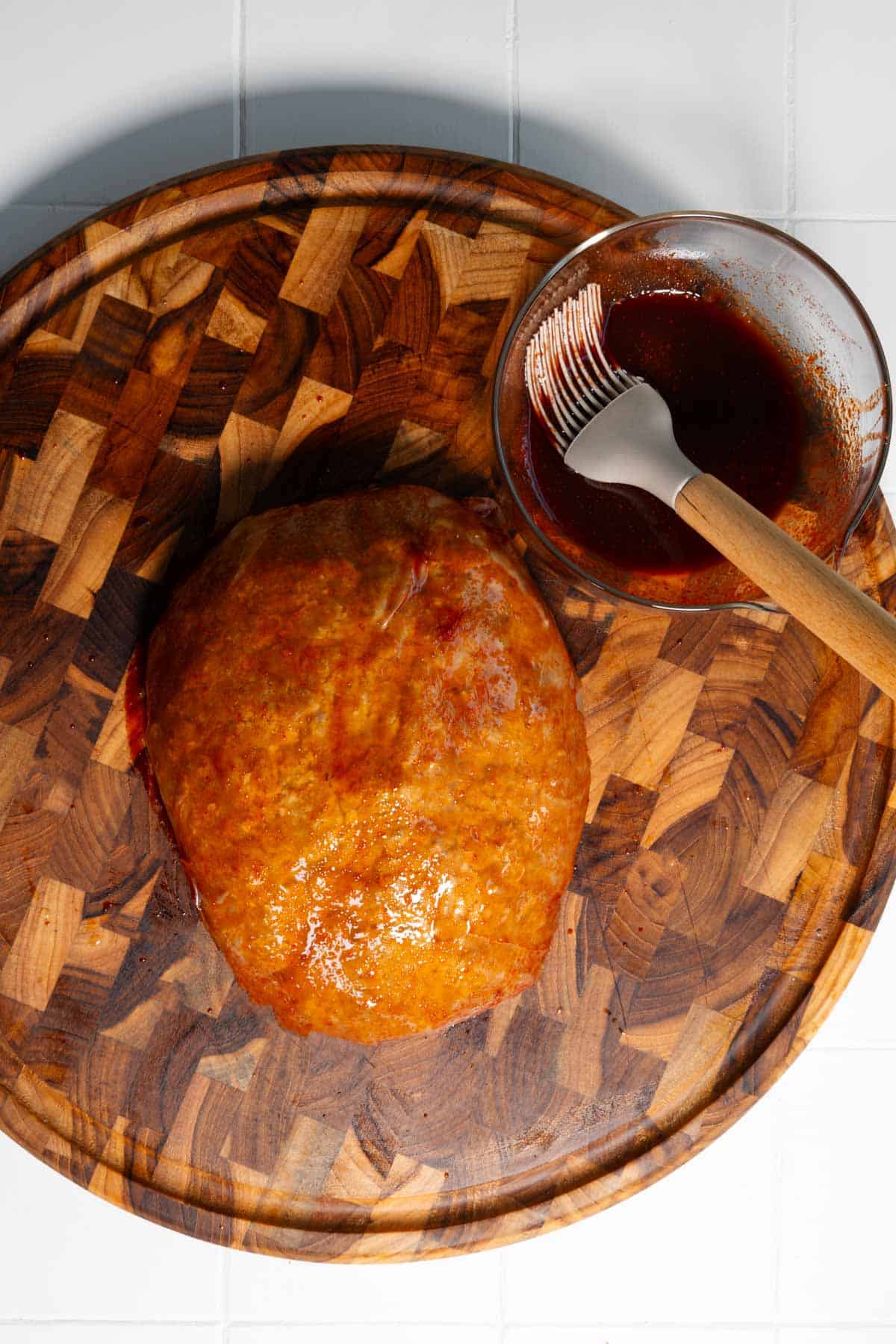 Basting vegan turkey on a wooden cutting board.