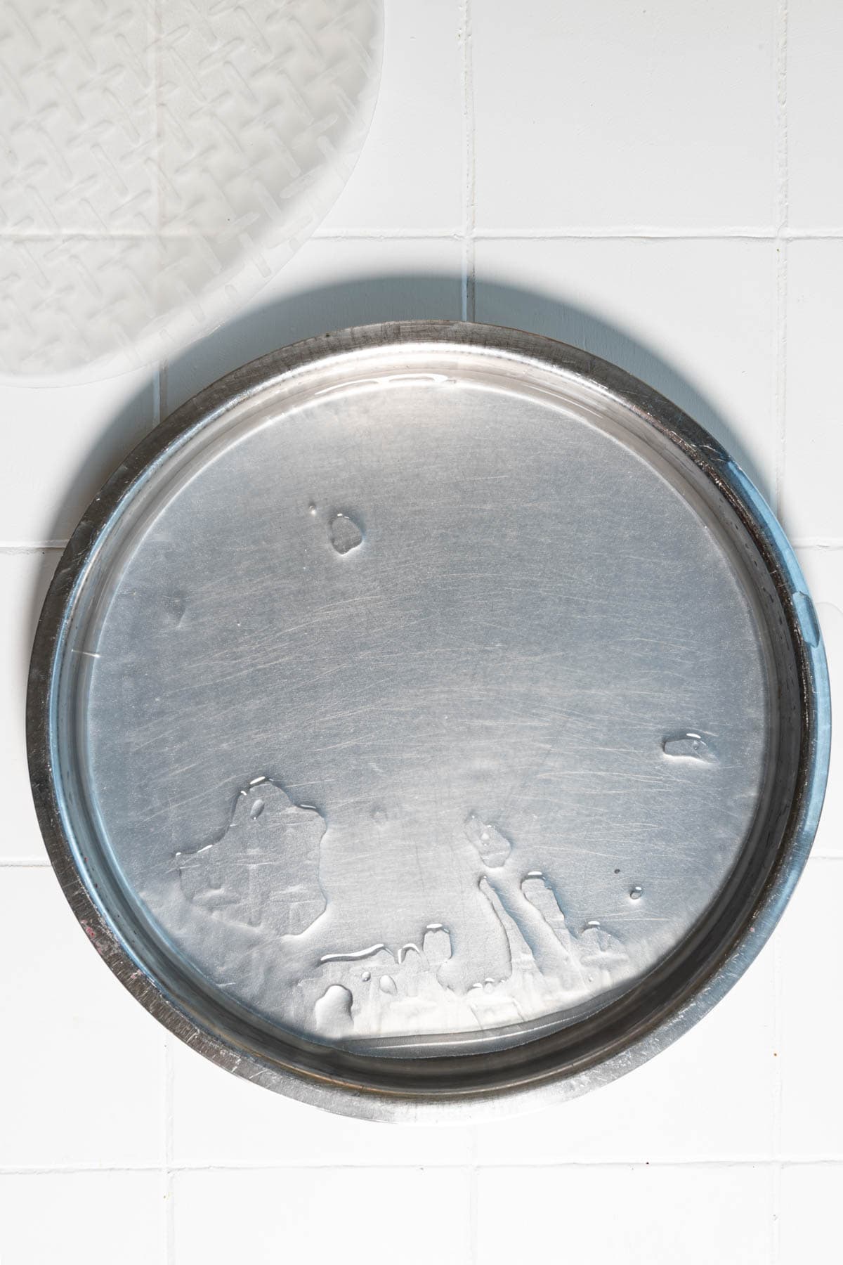 Wet rice paper in a stainless rimmed plate soaked in water.