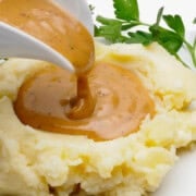 Vegan gluten-free gravy being poured onto mashed potatoes.