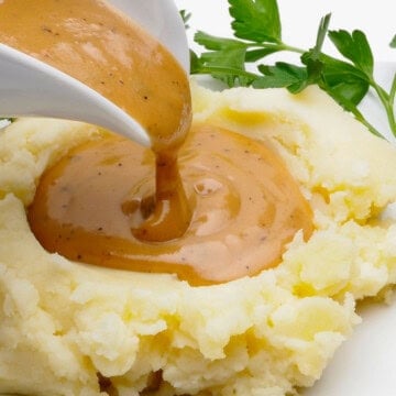 Vegan gluten-free gravy being poured onto mashed potatoes.