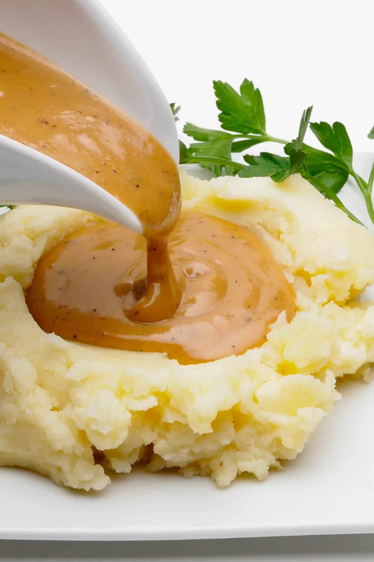Vegan gluten-free gravy being poured onto mashed potatoes.