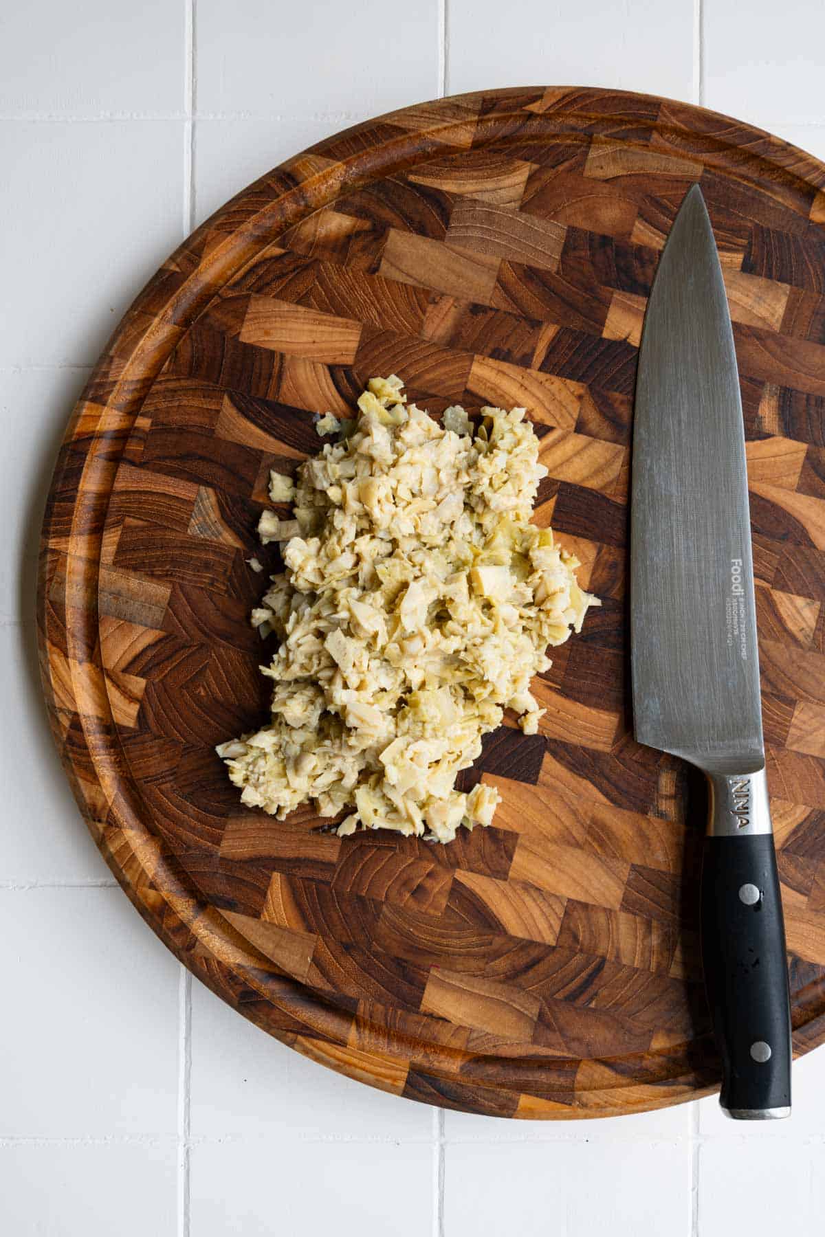 Chopped artichoke hearts on a wooden cutting board.