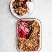 Gluten-free berry crisp with no added sugar in a glass baking dish and a serving on a white plate with yogurt.