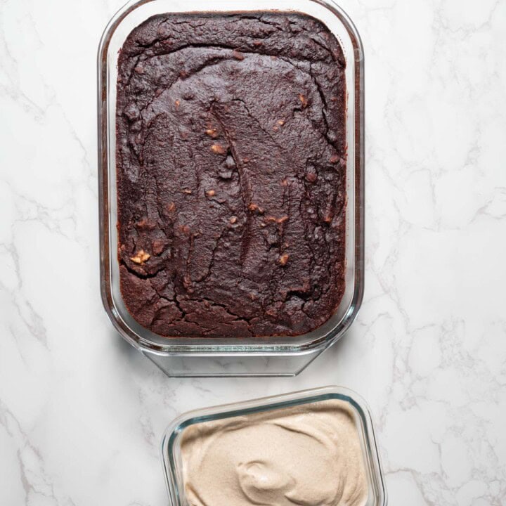 Healthy black bean brownies in a glass baking dish with a container of walnut cream.