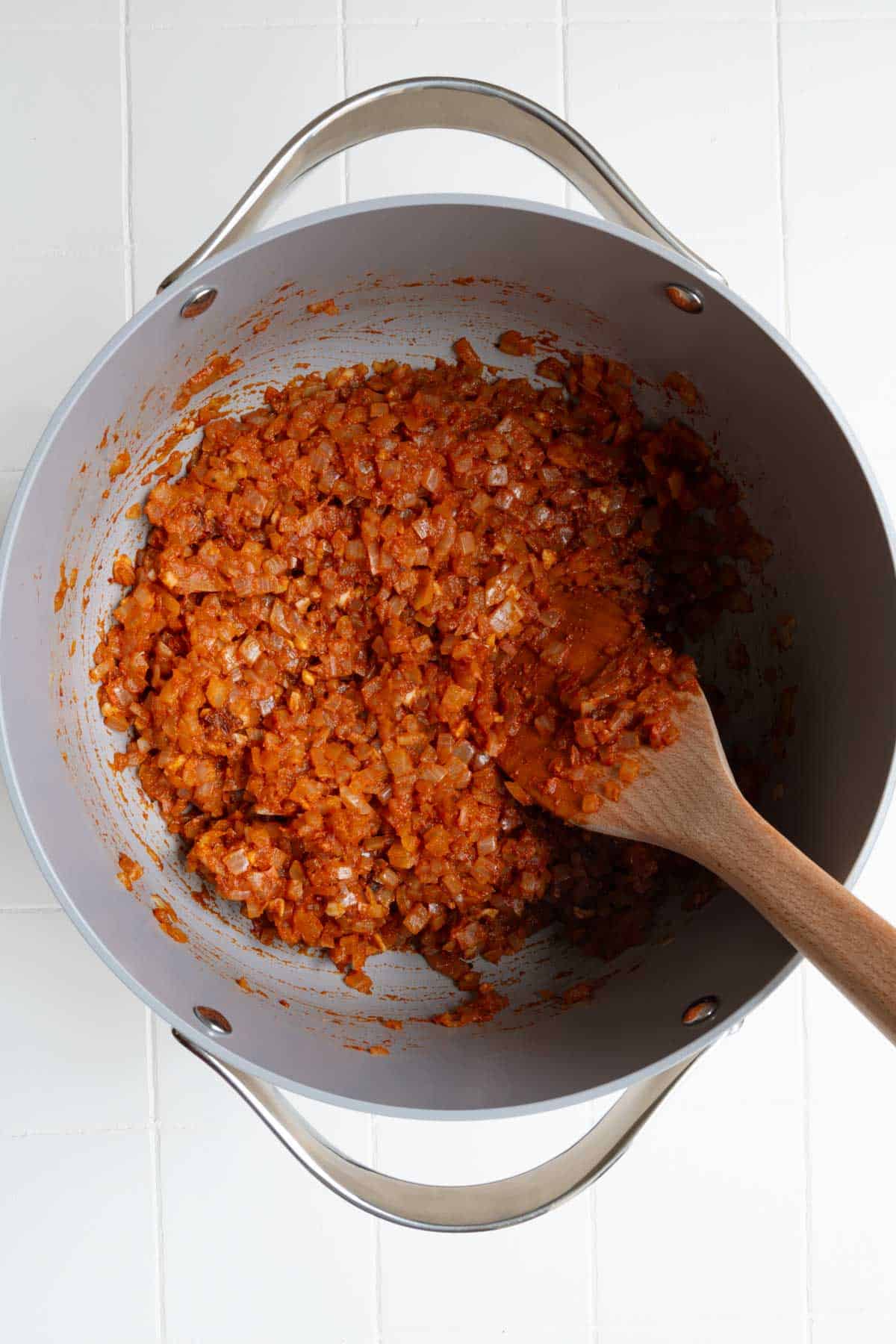 Cooked aromatics, sun-dried tomatoes, and tomato paste in a saucepan.