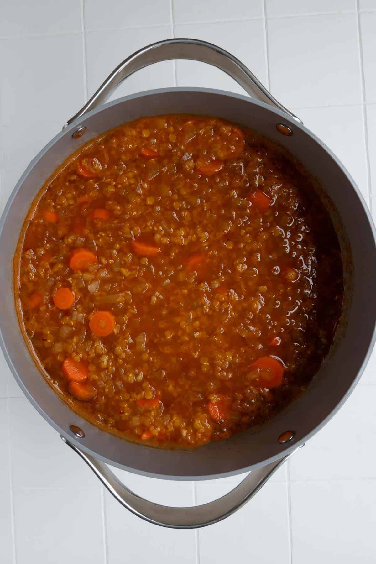 Cooked tomato lentil soup in a saucepan.