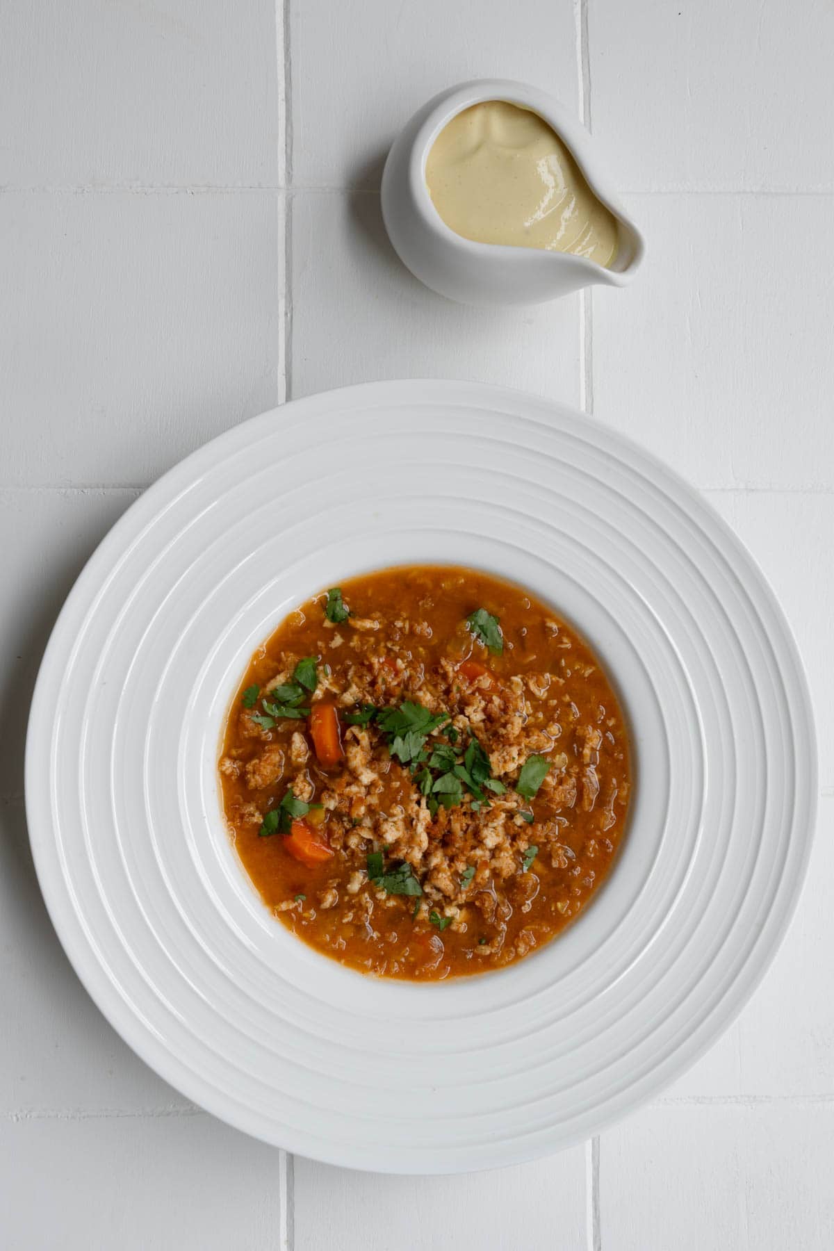 Tomato lentil soup with crumbled tofu in a white bowl.