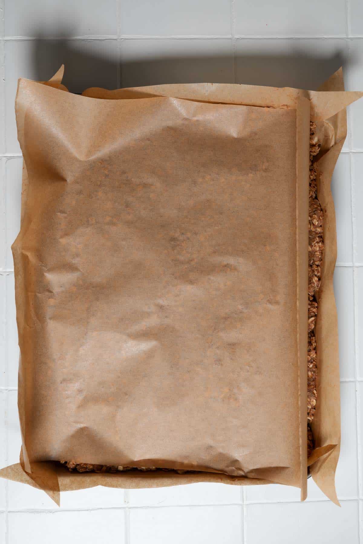 Parchment paper placed over the pressed oats, banana, hemp heart batter.