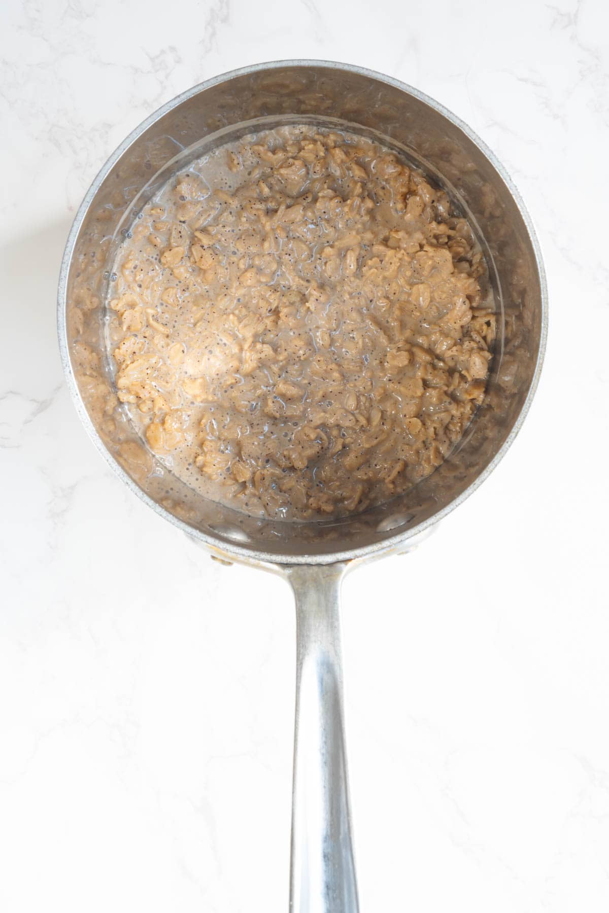 Oats, coffee, and nondairy milk cooking in a saucepan.