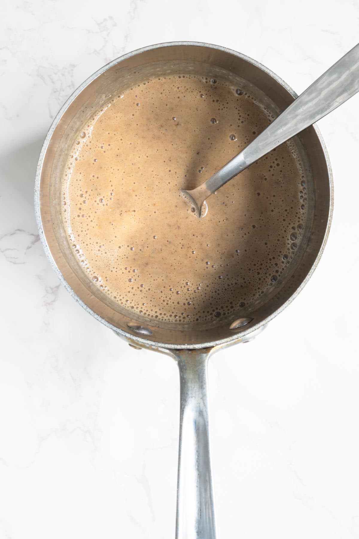 Oats, coffee, date caramel, and nondairy milk cooking in a saucepan.