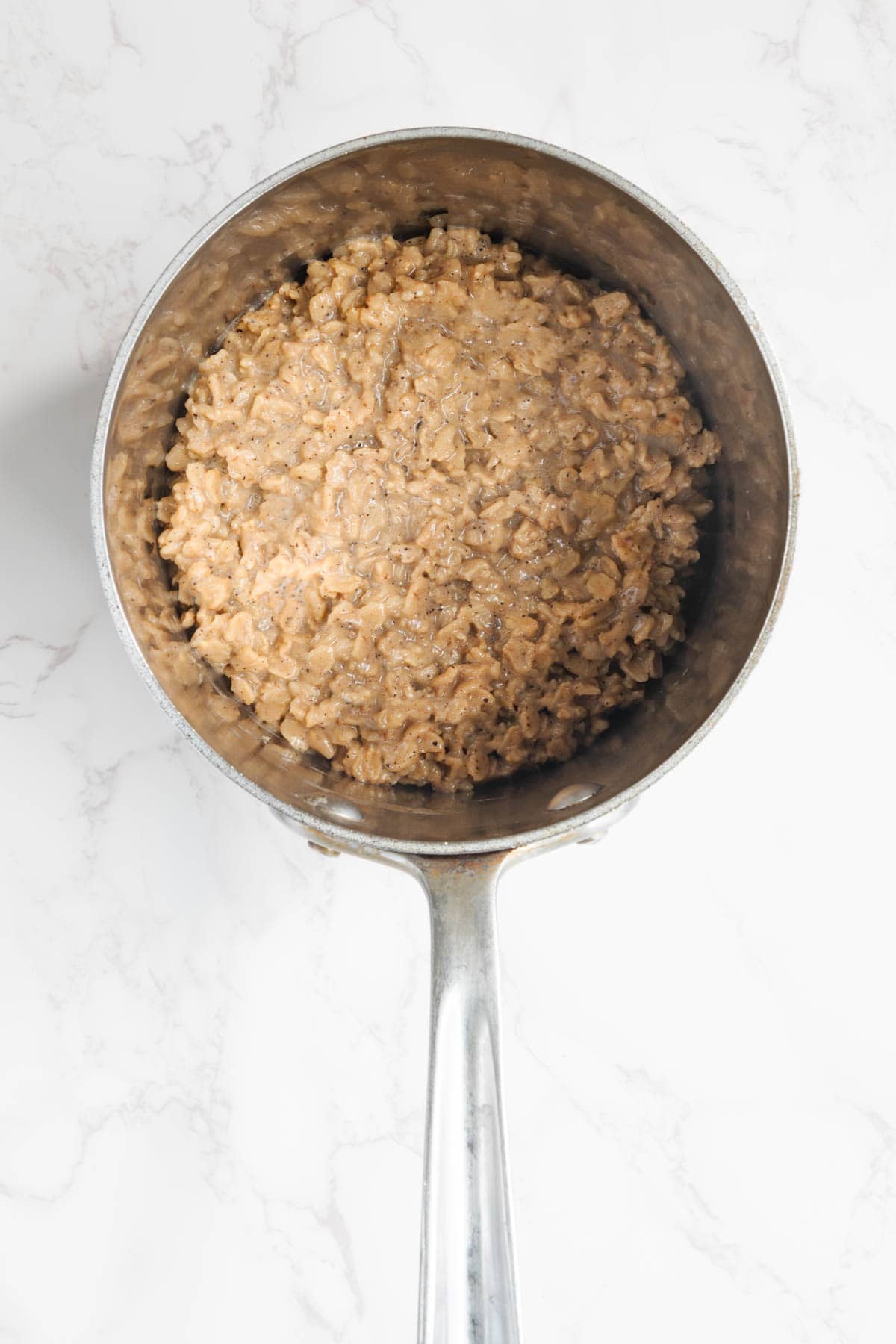 Cooked rolled oats in a stainless steel saucepan.