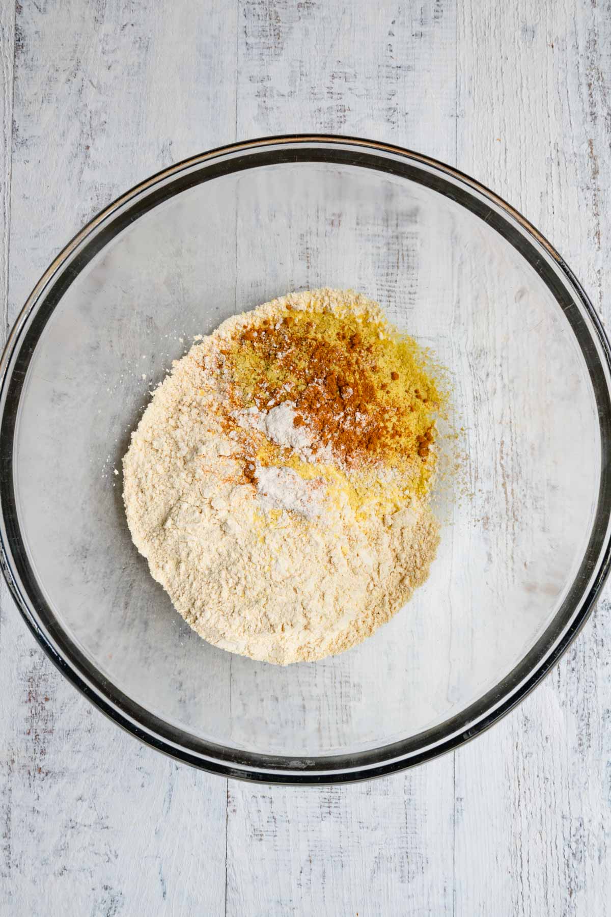 Chickpea flour, nutritional yeast, garlic powder, onion powder, salt and pepper, and turmeric in a glass bowl.