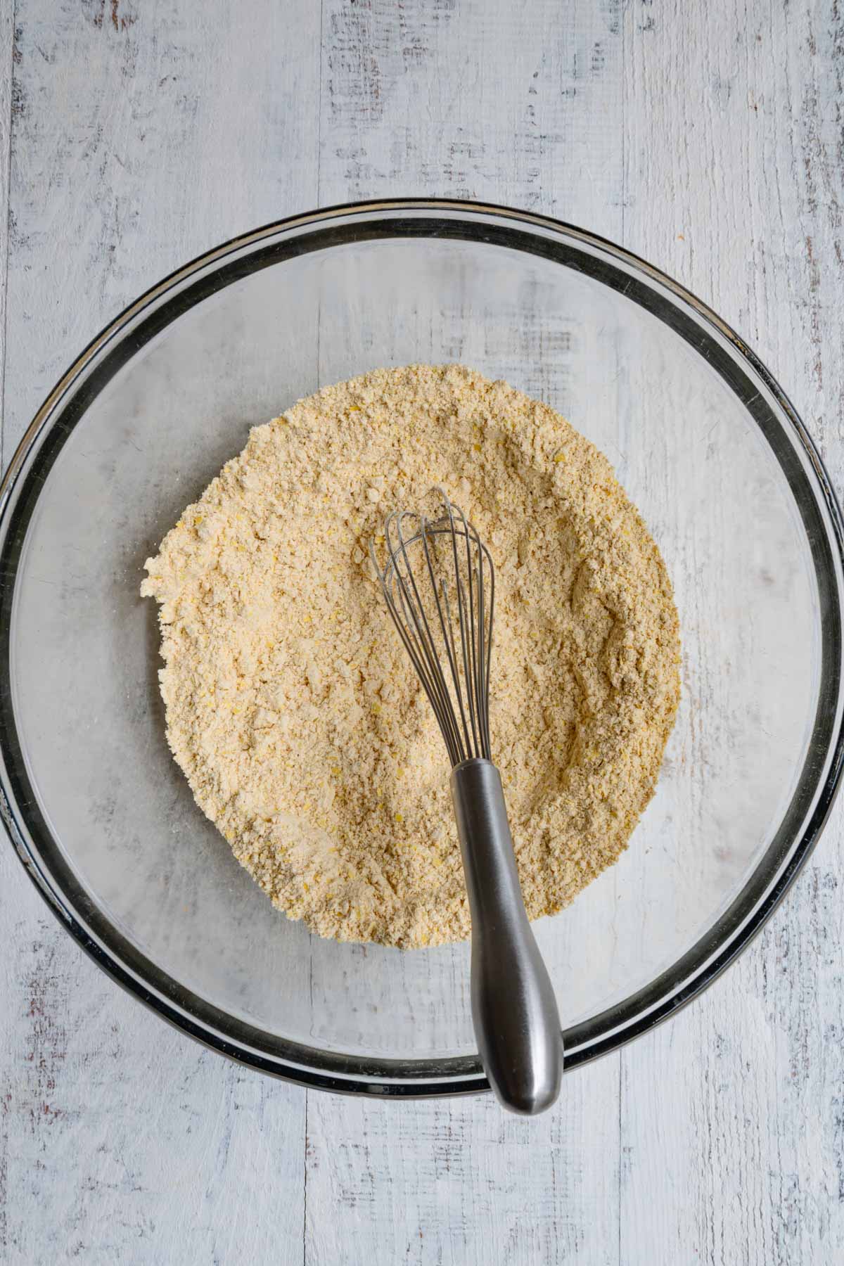 Mixed flour and seasonings in a glass bowl with a whisk.