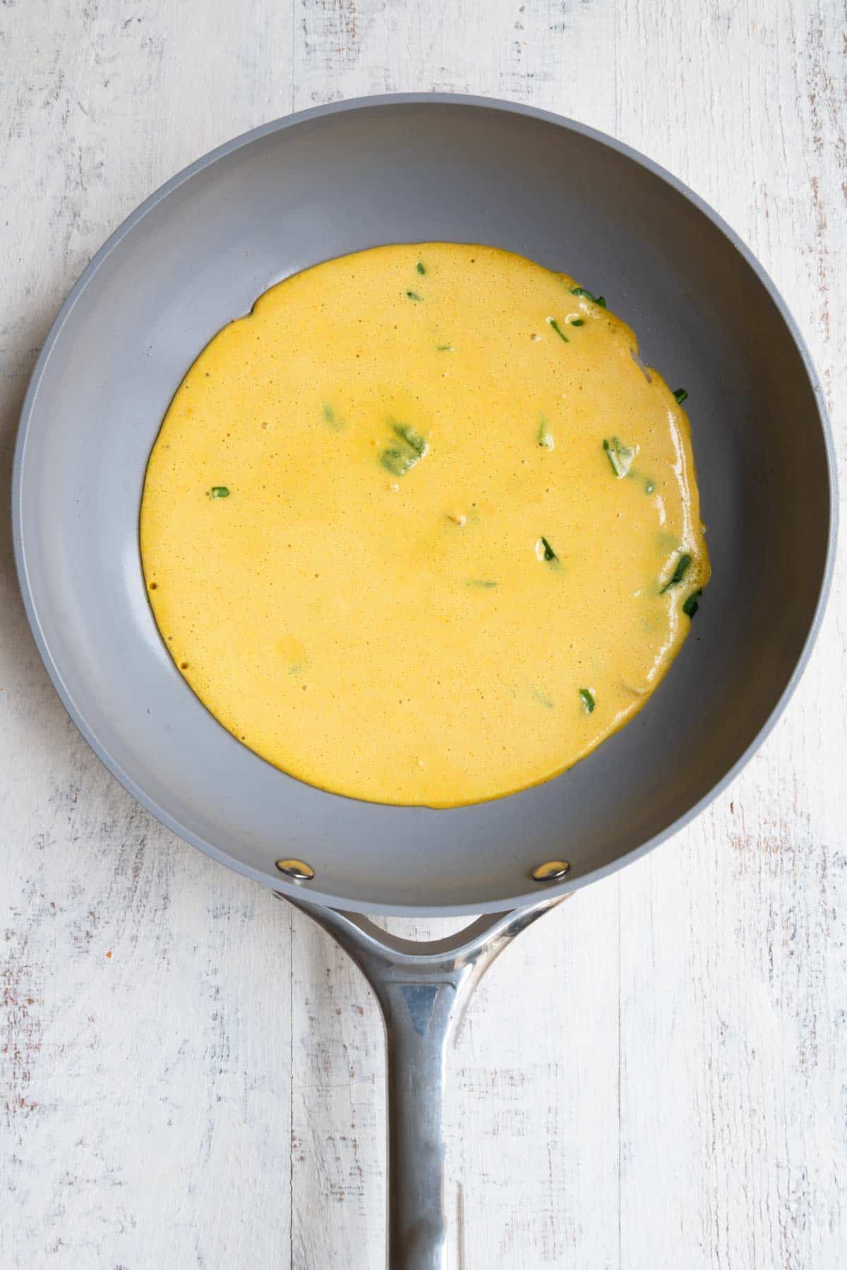 Chickpea flour (besan) egg mixture cooking in a nonstick skillet.