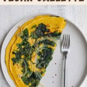High-protein vegan omelette with onion and spinach on a white plate with a fork.