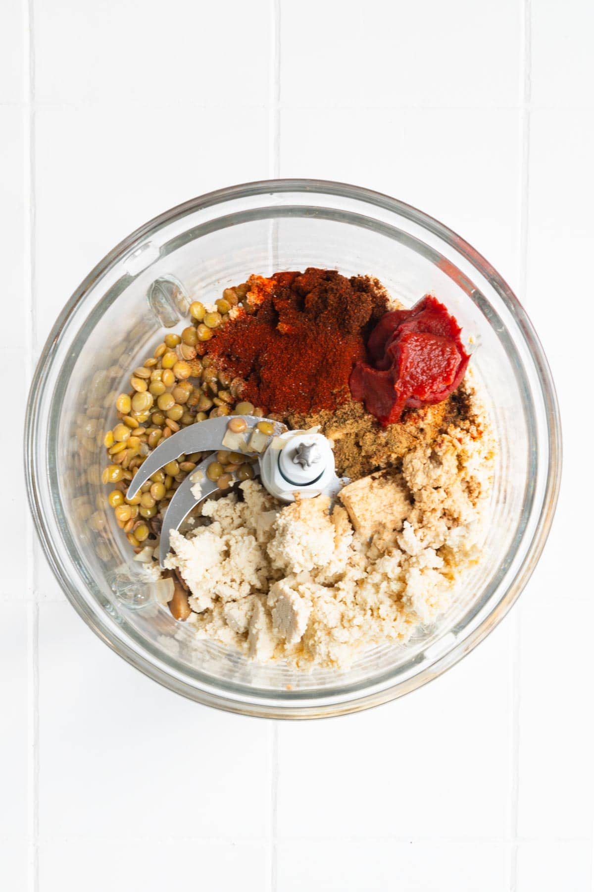 Tofu, lentils, tomato paste, and seasoning in a food processor.