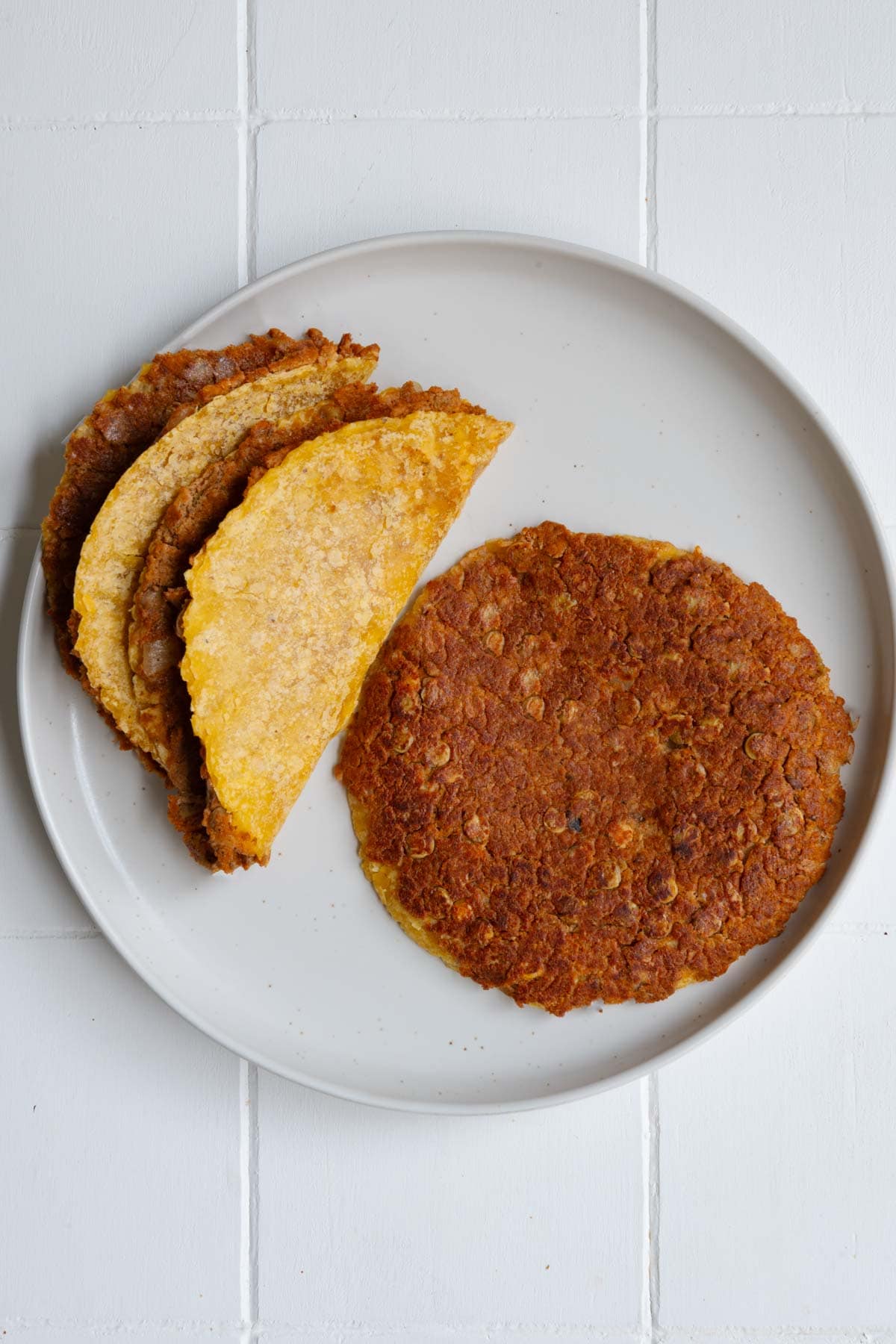 Three vegan smash burger tacos on a white plate.